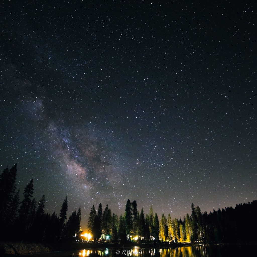 A mountain resort lit up under a sky of stars and the milky way