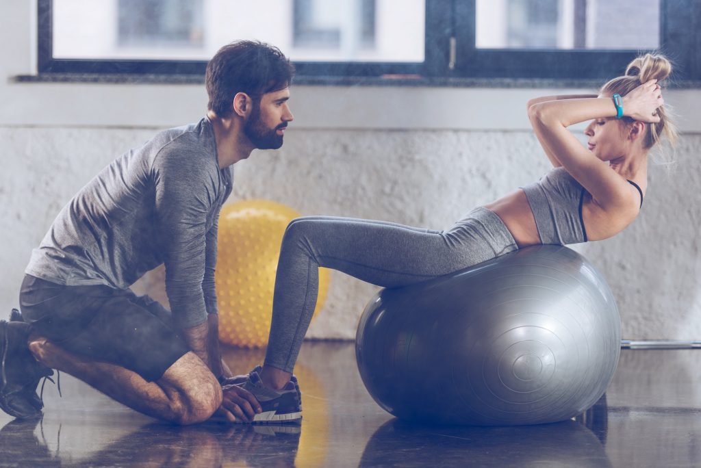 athletic young sportswoman doing abs on fitness ball at the gym, fitness couple gym concept