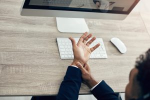 Hand pain, computer and business man working in office while suffering from arthritis, injury and m